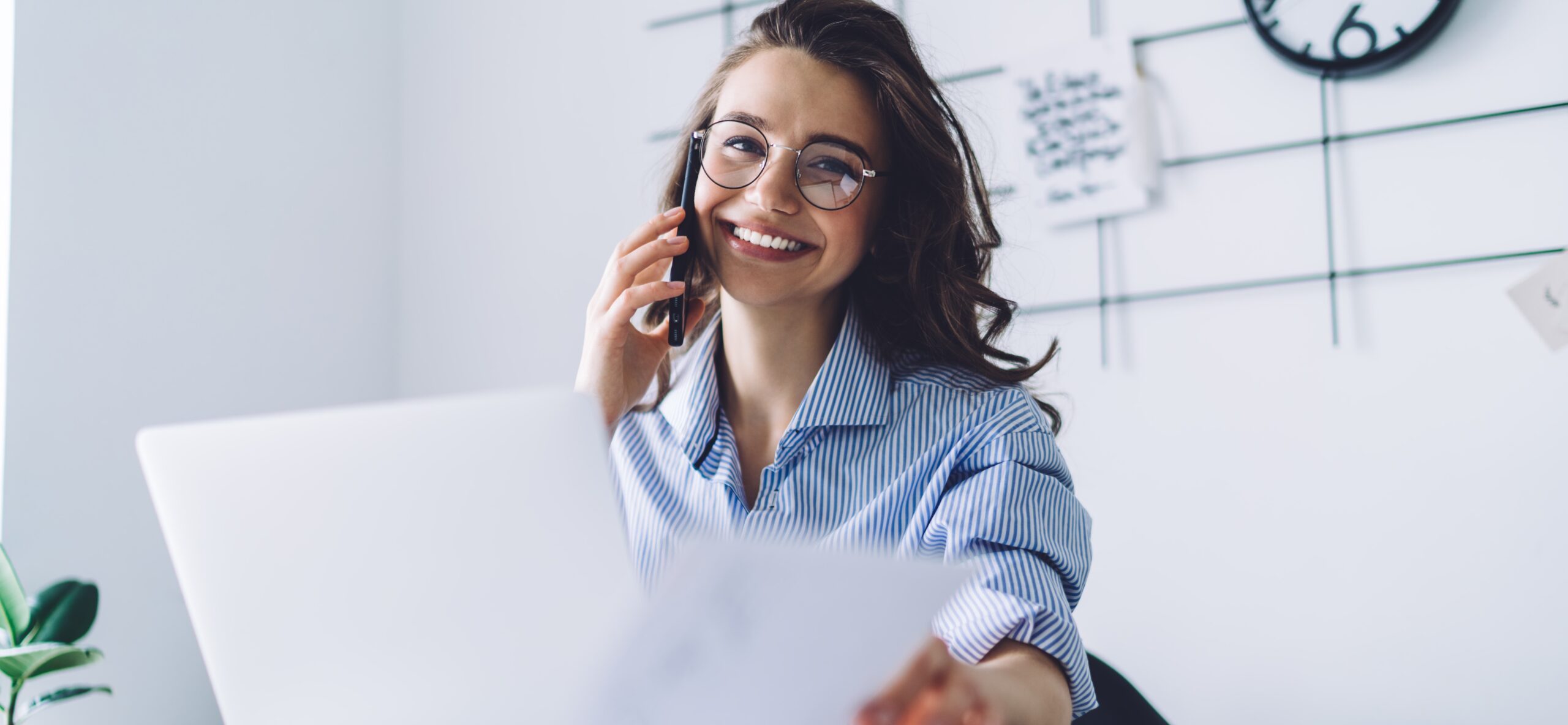 Young woman laughing while talking on cellphone in office